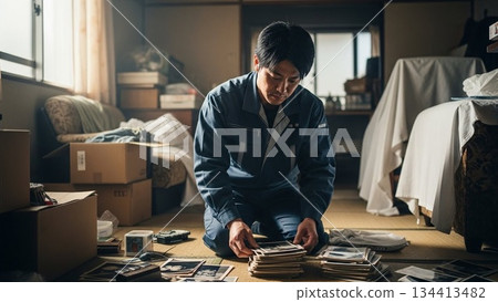 一名男工人在凌亂的房間裡整理物品。 134413482