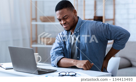 Pain In Back. African American Guy Having Backache Massaging Aching Lower Back Suffering From Pain Sitting At Workplace In Modern Office. Lumbar Ache. Health Problem Concept. Pain In Back. African American Guy Having Backache Massaging Aching Lower Back Suffering From Pain Sitting At Workplace In Modern Office. Lumbar Ache. Health Problem Concept. 134413493