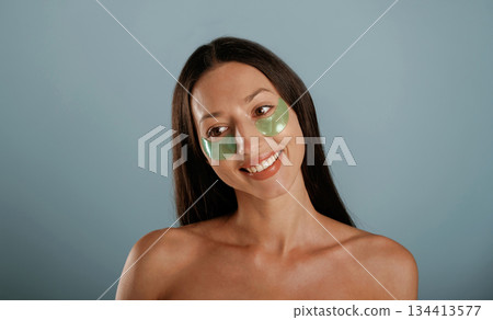 Against background. Eye patches. Young woman is in the studio 134413577
