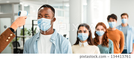 New Normal, Education, Pandemic And Health Concept. Teacher with contactless infrared thermometer gun measuring temperature of multiracial students in protective masks an entrance of classroom New Normal, Education, Pandemic And Health Concept. Teacher with contactless infrared thermometer gun measuring temperature of multiracial students in protective masks an entrance of classroom 134413761