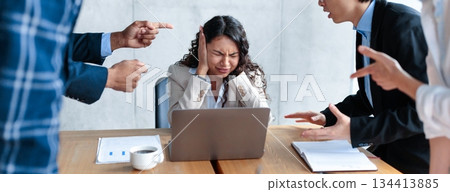 Conflict At Work. Unhappy Victimized Businesswoman Covering Ears Not Listening To Aggressive Colleagues Shouting At Her Sitting At Desk In Modern Office. Adult Bullying, Blaming, Communication Problem 134413885
