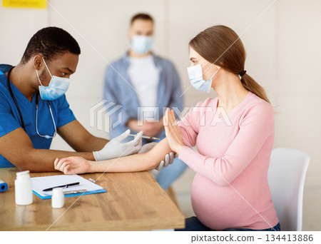 Expectant lady stopping medical worker from making covid-19 vaccine shot, opposing coronavirus immunization at clinic. Safety of vaccination during pregnancy concept Expectant lady stopping medical worker from making covid-19 vaccine shot, opposing coronavirus immunization at clinic. Safety of vaccination during pregnancy concept 134413886