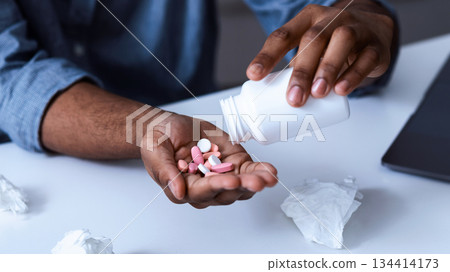 Closeup Of Pills And Medical Capsules In Black Man's Hand. African American Guy Taking Medication Sitting At Workplace Indoors. Medical Drugs Prescription Concept. Cropped, Selective Focus 134414173