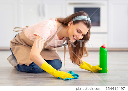 Happy Caucasian housewife in rubber gloves cleaning floor in kitchen, using cloth and detergent. Cheerful young maid housekeeping at home and having fun, doing domestic chores Happy Caucasian housewife in rubber gloves cleaning floor in kitchen, using cloth and detergent. Cheerful young maid housekeeping at home and having fun, doing domestic chores 134414497