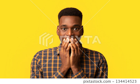 Closeup portrait of black surprised guy covering his mouth with excitement and looking at camera, african american man having wonder face expression, standing isolated on yellow background, free space 134414523