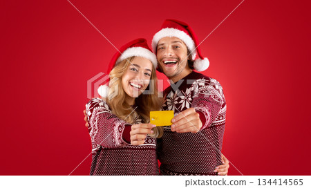 Shopping for Christmas. Smiling young couple showing contactless credit card over red background 134414565
