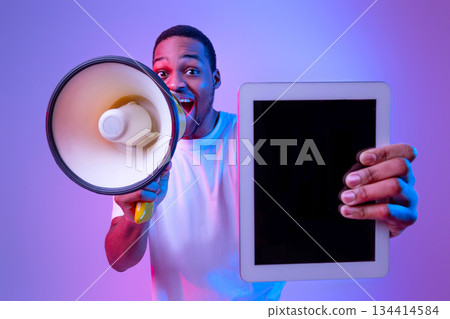 Excited African American Guy With Loudspeaker Holding Digital Tablet With Blank Black Screen, Making Announcement While Standing In Vivid Neon Light Over Purple Studio Background, Mockup Image Excited African American Guy With Loudspeaker Holding Digital Tablet With Blank Black Screen, Making Announcement While Standing In Vivid Neon Light Over Purple Studio Background, Mockup Image 134414584