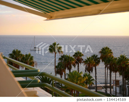 Seaside Balcony View with Sailboat at Sunset 134414589