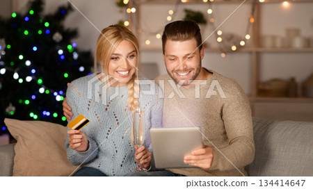 Happy couple doing Christmas shopping together, using digital tablet and credit card, copy space Happy couple doing Christmas shopping together, using digital tablet and credit card, copy space 134414647