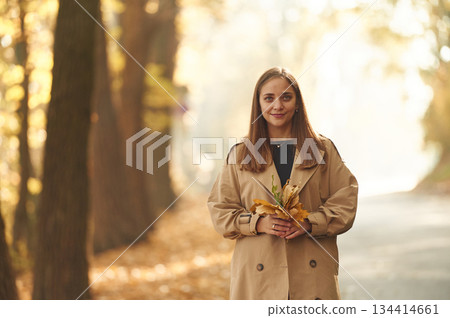 Wellbeing, holding fallen leaves. Happy woman is in the autumn forest Wellbeing, holding fallen leaves. Happy woman is in the autumn forest 134414661