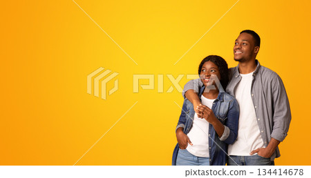 Nice Offer. Young happy black couple embracing and looking at copy space with interest, cheerful millennial man and woman standing isolated over yellow background, panorama with copy space Nice Offer. Young happy black couple embracing and looking at copy space with interest, cheerful millennial man and woman standing isolated over yellow background, panorama with copy space 134414678