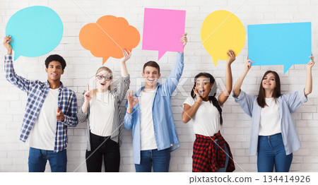 Speech bubbles. Happy friends holding empty placards over white brick wall Speech bubbles. Happy friends holding empty placards over white brick wall 134414926