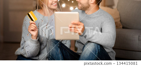 Beautiful young couple using digital tablet, shopping online during Christmas at home, woma holding credit card 134415081