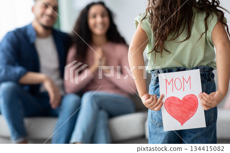 Mother's Day Gift. Cute Little Girl Prepare Greeting Card With Big Drawn Red Heart To Her Loving Mom, Kid Holding Her Present Behind Back, Congratulating Her Mommy With Holiday, Selective Focus Mother's Day Gift. Cute Little Girl Prepare Greeting Card With Big Drawn Red Heart To Her Loving Mom, Kid Holding Her Present Behind Back, Congratulating Her Mommy With Holiday, Selective Focus 134415082
