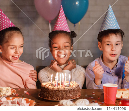 African-american girl celebrating birthday and making wish, looking at cake 134415098
