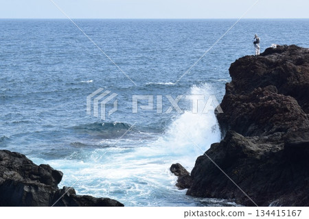 Fisherman standing on rocks 134415167