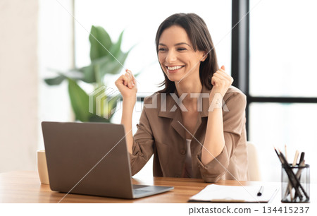 Great Success. Happy manager using laptop, gesturing, celebrating success with clenched fists at office, copyspace Great Success. Happy manager using laptop, gesturing, celebrating success with clenched fists at office, copyspace 134415237