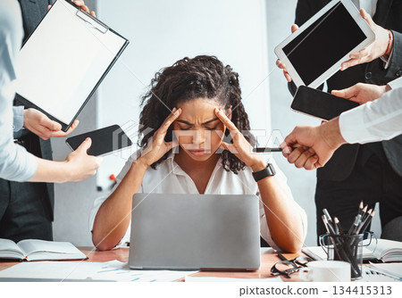 Multitasking. Overworked Afro Businesswoman Sitting Touching Head Ignoring Colleagues Tired Of Multiple Tasks At Work In Modern Office. 134415313