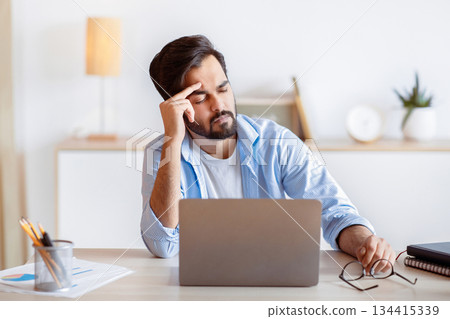 Overworked Arab Businessman Suffering From Migraine At Work, Having Strong Headache. Stressed Millennial Eastern Man Feeling Unwell While Sitting At Workplace In Modern Office, Copy Space Overworked Arab Businessman Suffering From Migraine At Work, Having Strong Headache. Stressed Millennial Eastern Man Feeling Unwell While Sitting At Workplace In Modern Office, Copy Space 134415339
