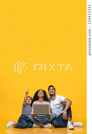 Great Offer. Joyful Arab Family Of Three With Laptop Pointing Up At Copy Space Above Their Heads, Interested Middle Eastern Parents And Little Daughter Looking At Free Place For Advertisement 134415341