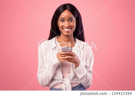 Portrait of smiling young black woman browsing web on smartphone. Pretty African American lady using mobile phone for online studies or work, chatting with friends on internet Portrait of smiling young black woman browsing web on smartphone. Pretty African American lady using mobile phone for online studies or work, chatting with friends on internet 134415394