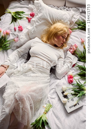 Elegant fashion model lying peacefully amid vibrant tulips and gentle sunlight on soft linens Elegant fashion model lying peacefully amid vibrant tulips and gentle sunlight on soft linens 134415753