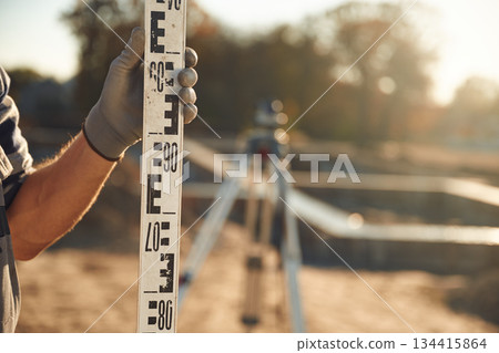 Measuring plank. Close up view of worker on the construction site Measuring plank. Close up view of worker on the construction site 134415864