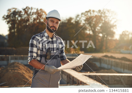 Holding plan in hands. Worker is on the construction site at daytime 134415881