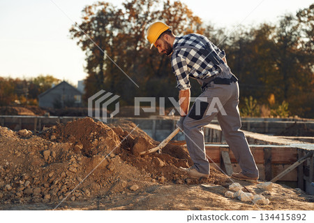 Soil, digging with a shovel. Worker is on the construction site at daytime 134415892