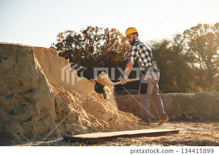 The soil, digging with shovel. Worker is on the construction site at daytime 134415899
