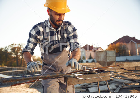 Working with metal rod. Man is on the construction site at daytime 134415909