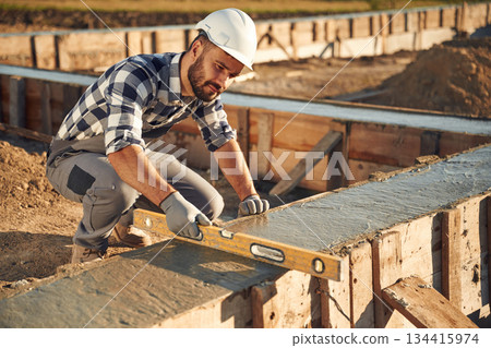 Tool for measuring leveling of surface. Worker is on the construction site at daytime Tool for measuring leveling of surface. Worker is on the construction site at daytime 134415974