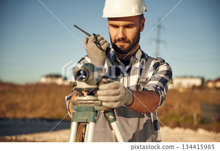 Using the geodetic optical level. Worker is on the construction site at daytime 134415985