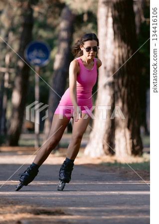 Woman in pink sportwear roller skating in the park, active lifestyle concept. 134416106