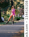 Woman in pink sportwear roller skating in the park, active lifestyle concept. 134416108