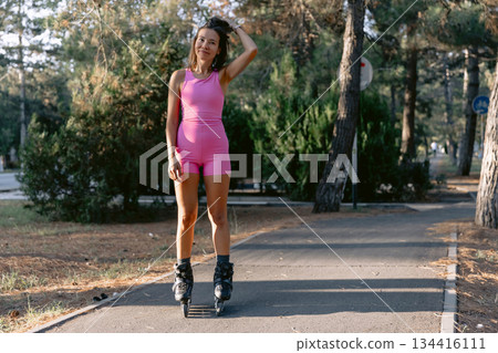 Woman in pink sportwear roller skating in the park, active lifestyle concept. 134416111