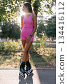 Woman in pink sportwear roller skating in the park, active lifestyle concept. 134416112