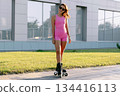 Portrait of young woman in pink outdoor on roller skates at sunset in the park. 134416113