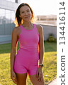 Portrait of young woman in pink outfit enjoying outdoor activity at sunset 134416114