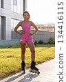 Portrait of young woman in pink outdoor on roller skates at sunset in the park. 134416115