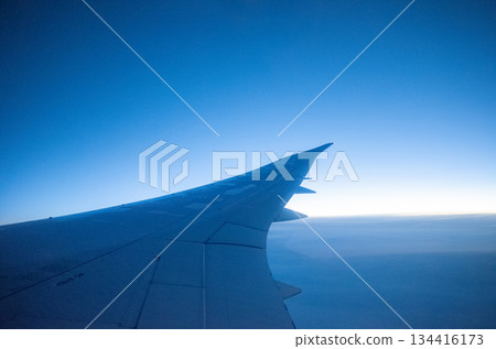 A view of the aircraft wing, the expansive blue sky and the horizon from a window seat on an airplane 134416173