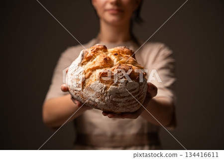 Artisan baker presenting rustic handmade bread loaf, showcasing traditional craftsmanship and natural quality 134416611