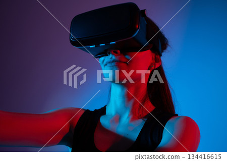 Woman exploring virtual reality with headset in futuristic blue and red light environment innovation 134416615
