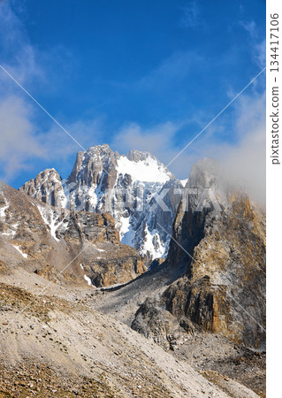 High mountain peak with snow and rock under a blue sky, representing nature adventure and majestic landscape. High mountain peak with snow and rock under a blue sky, representing nature adventure and majestic landscape. 134417106