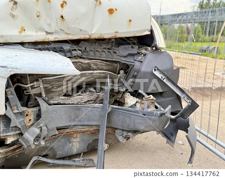 This minibus was significantly damaged as a result of a serious head-on collision. A seriously damaged grey minibus, which shows significant collision marks in the front and extensive rust marks. 134417762
