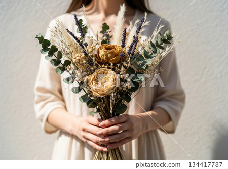 A woman with a gentle atmosphere holding a bouquet of natural dried flowers 134417787