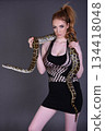 Beautiful redhead girl posing with her pet snake in the studio 134418048