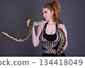 Beautiful redhead girl posing with her pet snake in the studio 134418049