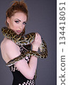 Beautiful redhead girl posing with her pet snake in the studio 134418051