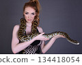 Beautiful redhead girl posing with her pet snake in the studio 134418054